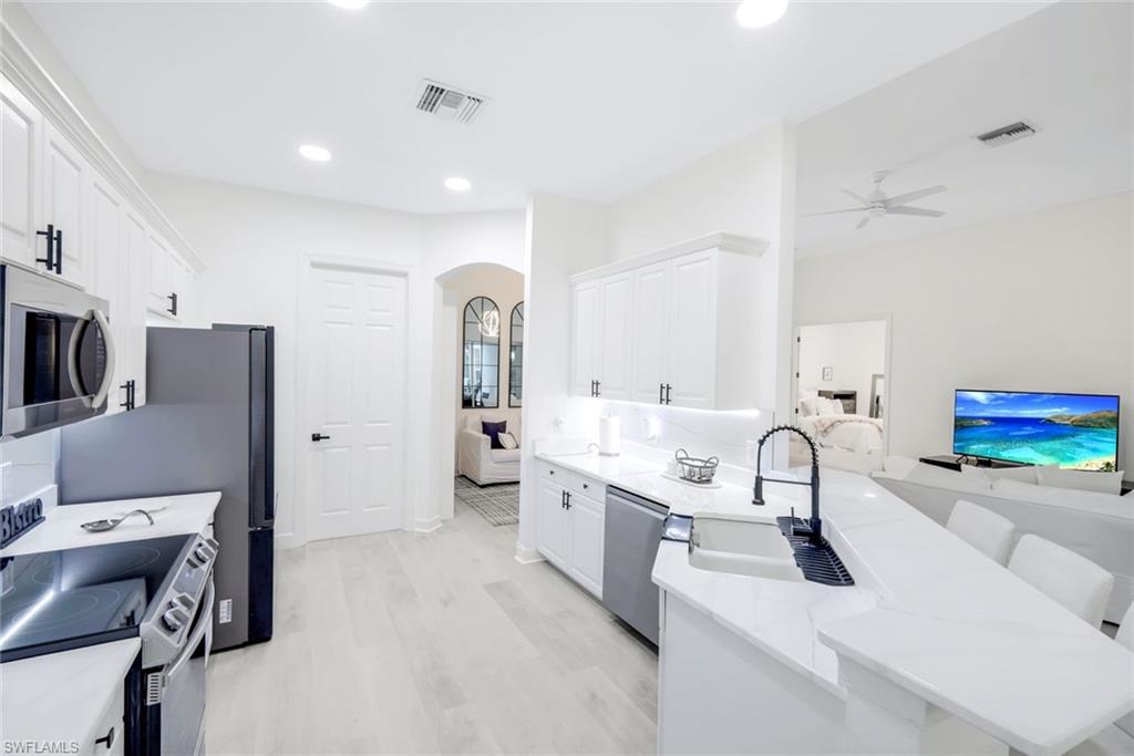 16188 Parque Lane Naples, FL 34110 - Photo 12 of 29 a kitchen with stainless steel appliances a sink dishwasher a refrigerator a stove and a sink with wooden floor