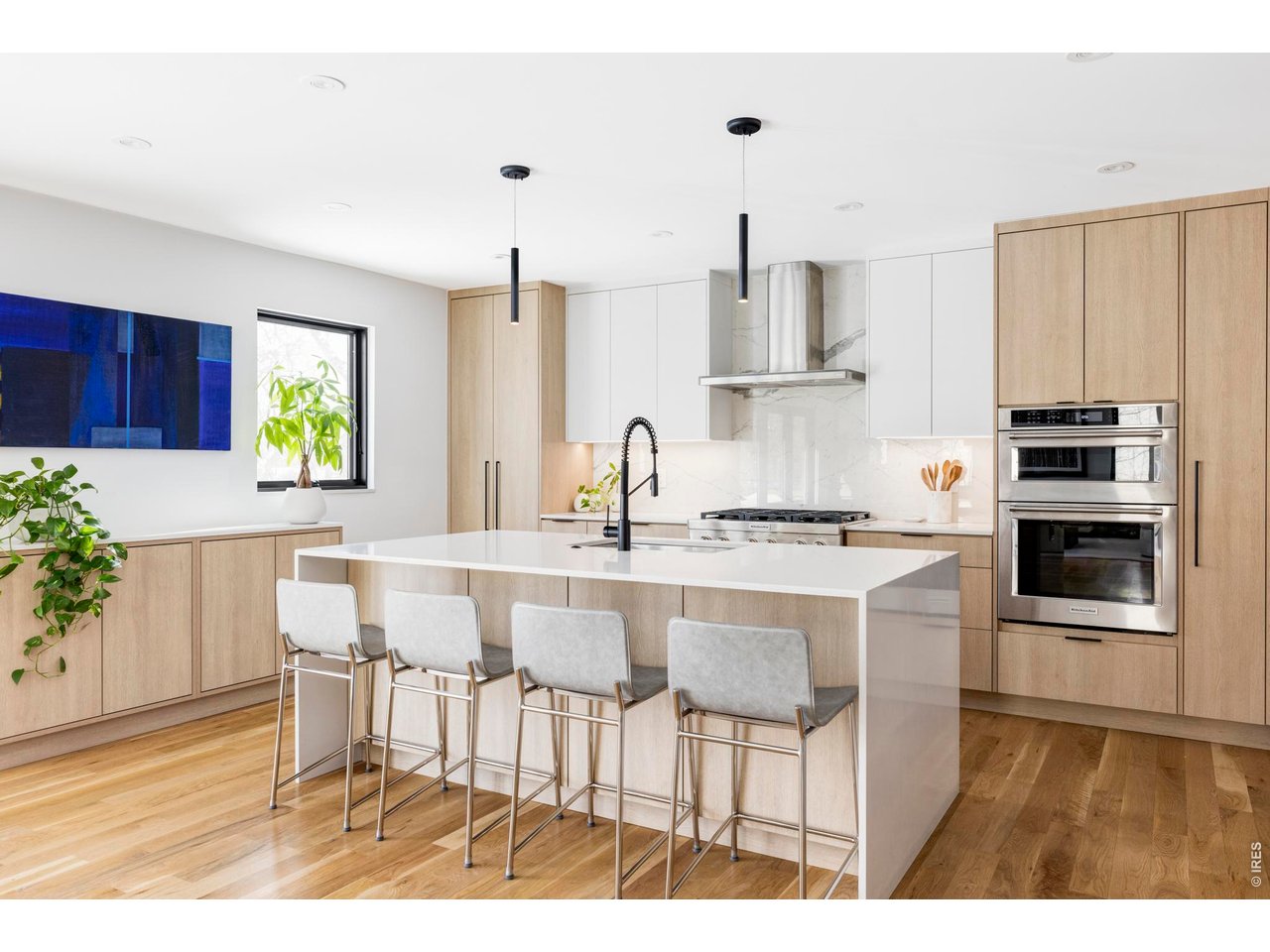 3560 16th Street Boulder, CO 80304 - Photo 8 of 36 The chef's kitchen is a masterpiece of modern design, featuring custom flat-panel cabinetry in a sophisticated blend of white and natural wood tones, marble-inspired backsplash, and a waterfall island with additional cabinetry.