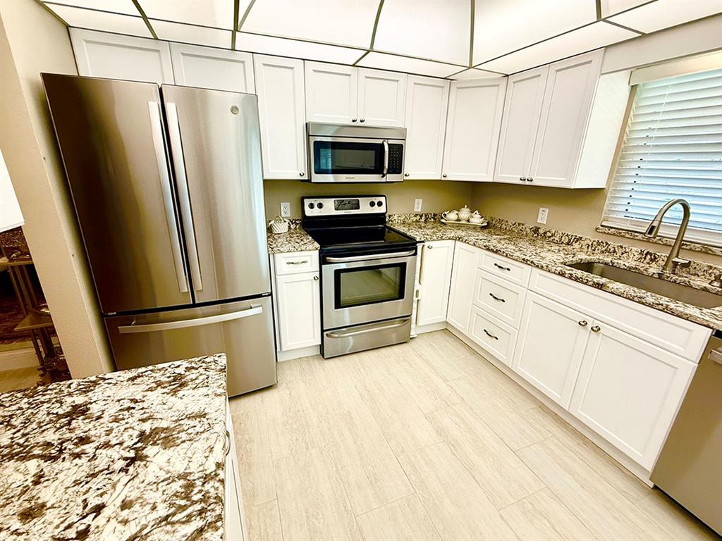 4455 Duhme Road, Unit 103 St. Petersburg, FL 33708 - Photo 8 of 37 a kitchen with granite countertop a refrigerator stove and microwave