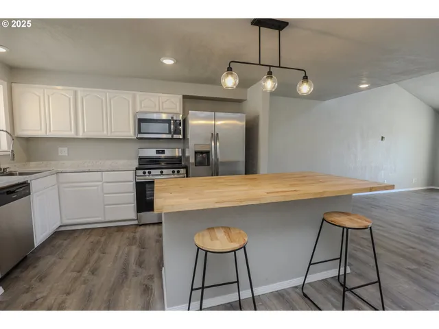 a kitchen with stainless steel appliances a table chairs refrigerator and microwave