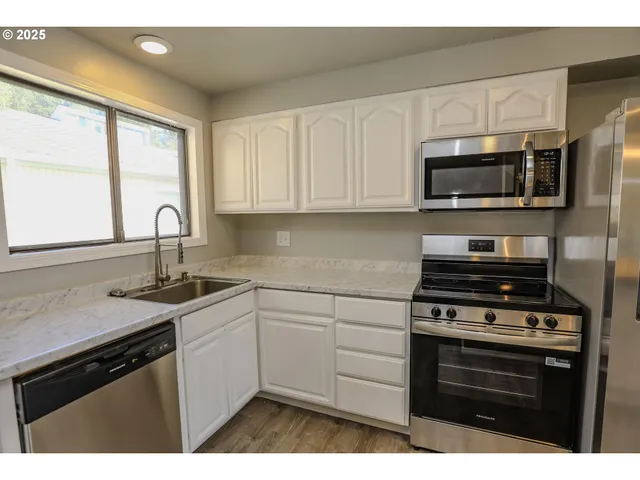 a kitchen with stainless steel appliances granite countertop a sink stove and microwave