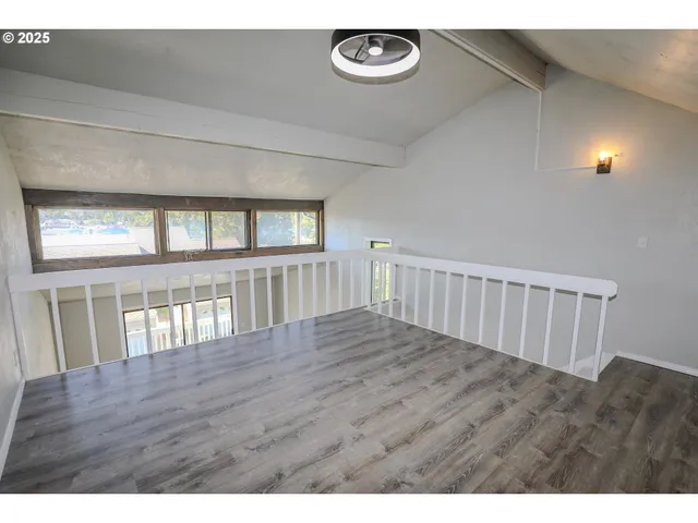 a view of an empty room with wooden floor and windows
