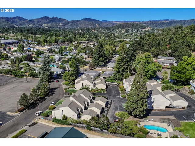 an aerial view of a city with lots of residential buildings and mountain view in back