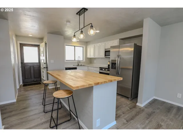 a kitchen with stainless steel appliances kitchen island a table chairs in it and wooden floors
