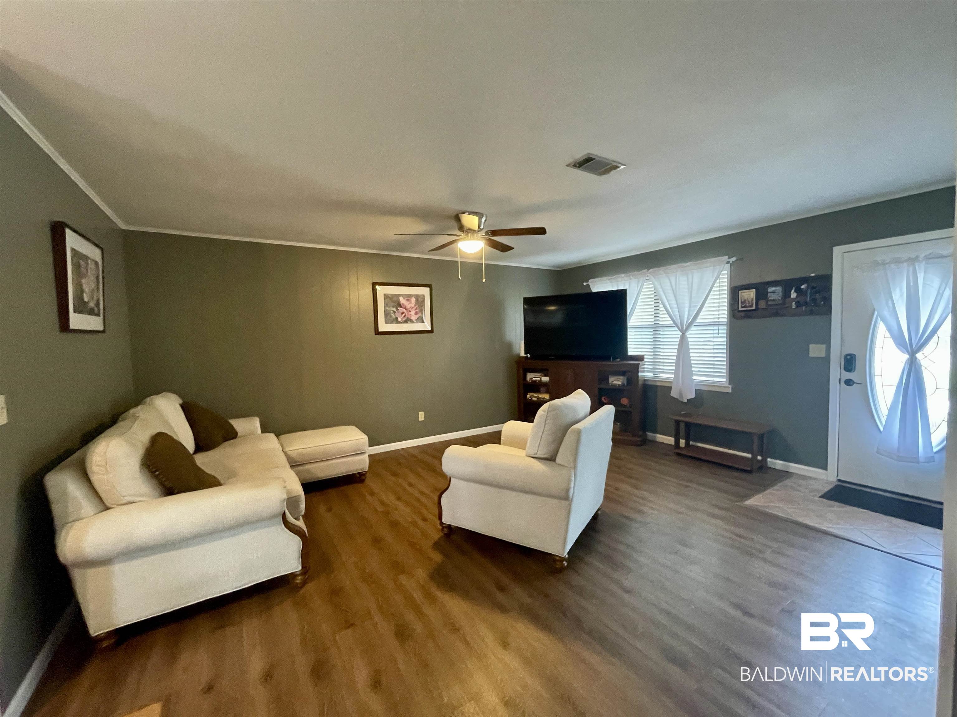 2274 Foshee Road Brewton, AL 36426 - Photo 4 of 23 Living room with ceiling fan, dark wood-style flooring, and crown molding