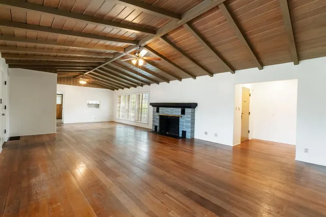 a view of empty room with wooden floor and fireplace