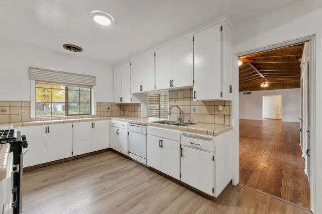 a kitchen with granite countertop white cabinets white stainless steel appliances with a sink and dishwasher