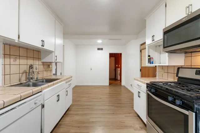 a kitchen with stainless steel appliances a sink dishwasher stove and refrigerator