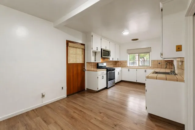 a kitchen with a sink wooden floors and white cabinets