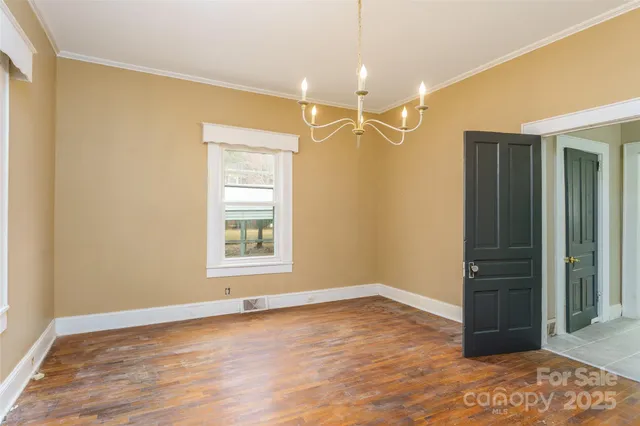 an empty room with wooden floor cabinet and windows