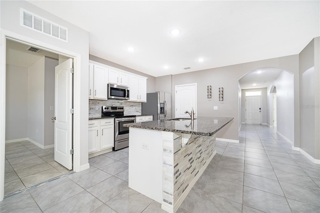 3102 Bethpage Loop Mount Dora, FL 32757 - Photo 12 of 29 a kitchen with stainless steel appliances kitchen island granite countertop a sink and cabinets