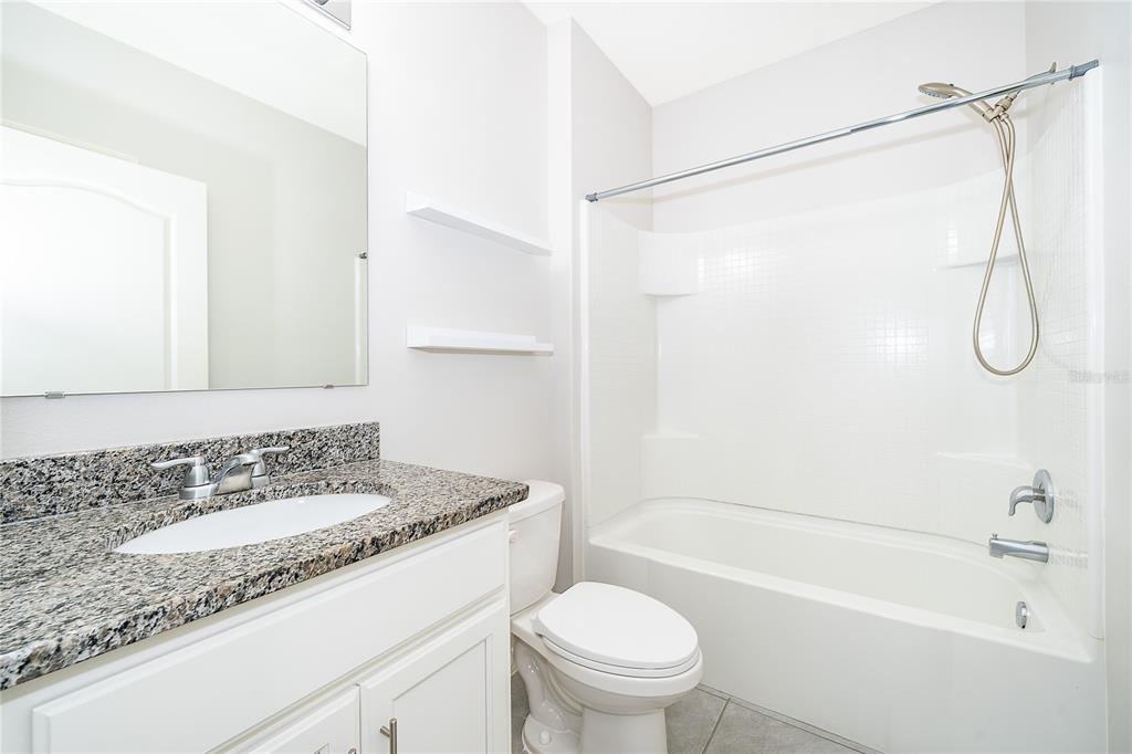3102 Bethpage Loop Mount Dora, FL 32757 - Photo 19 of 29 a bathroom with a granite countertop sink a toilet and shower