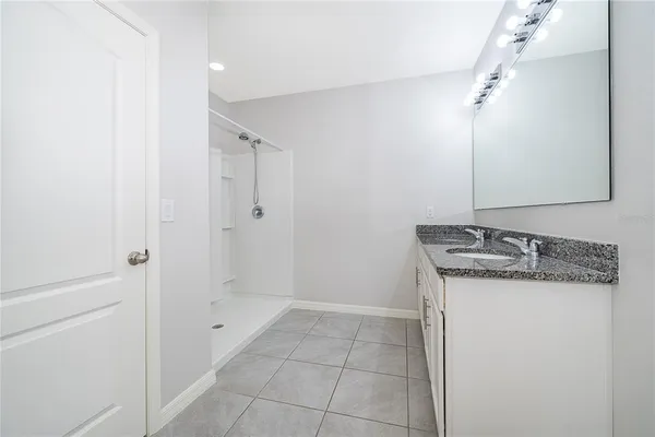 a bathroom with a granite countertop sink a mirror and shower
