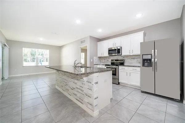 a kitchen with granite countertop a stove top oven a sink a counter top space and cabinets