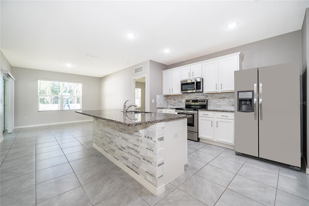 3102 Bethpage Loop Mount Dora, FL 32757 - Photo 10 of 29 a kitchen with granite countertop a stove top oven a sink a counter top space and cabinets