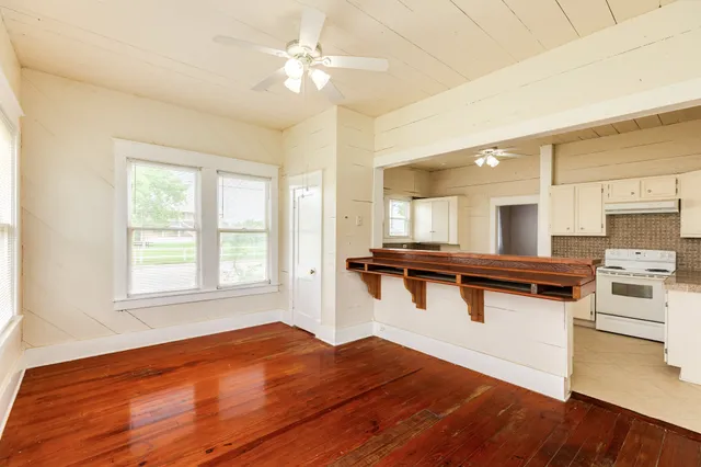 a view of a kitchen with kitchen island a sink wooden floor and a large window