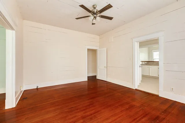 an empty room with wooden floor and a ceiling fan