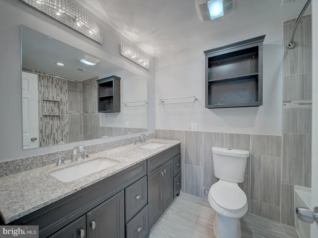 a bathroom with a granite countertop toilet sink and mirror