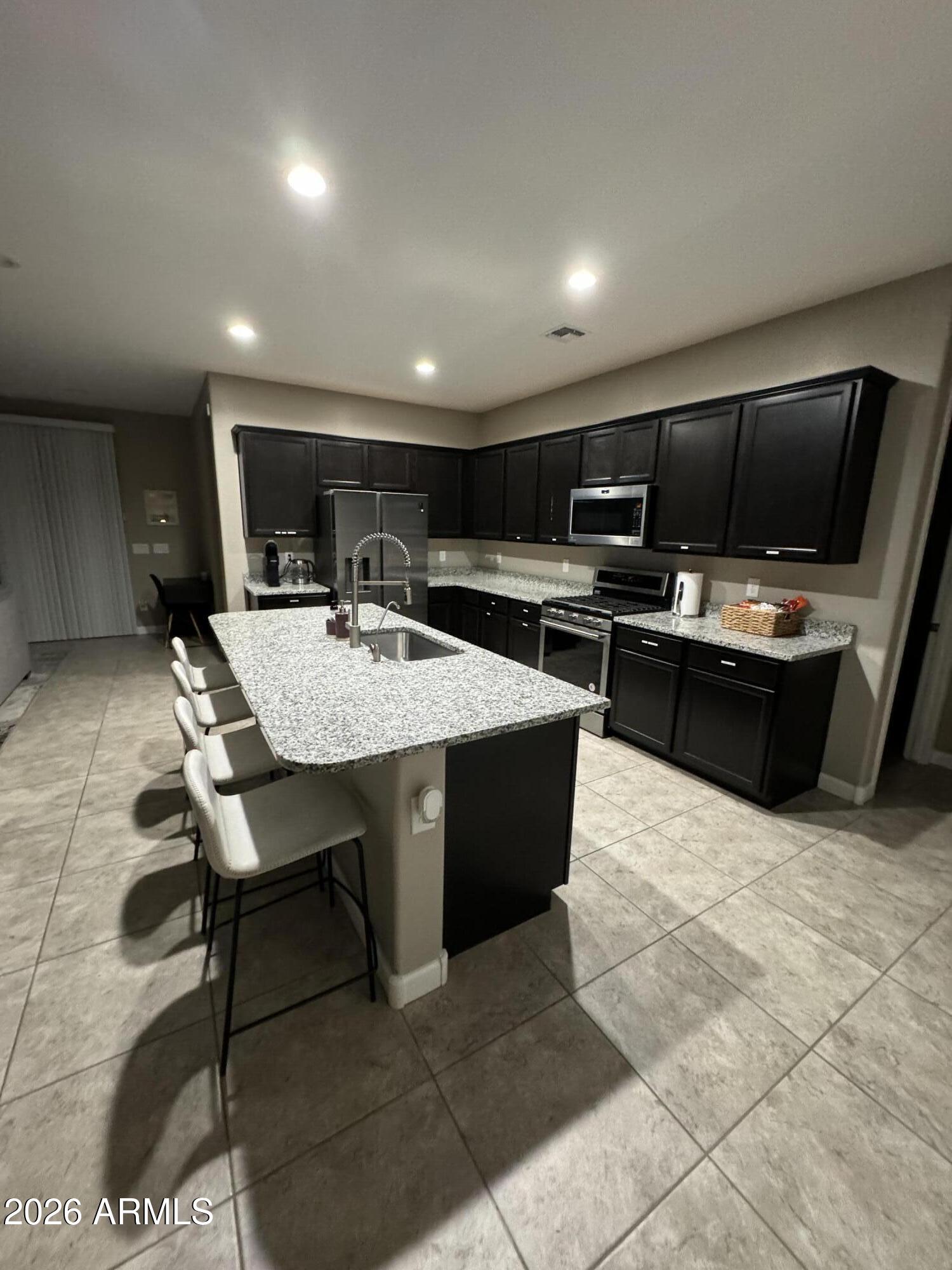 18735 North Ravello Road Maricopa, AZ 85138 - Photo 2 of 50 a kitchen with a table chairs refrigerator and microwave