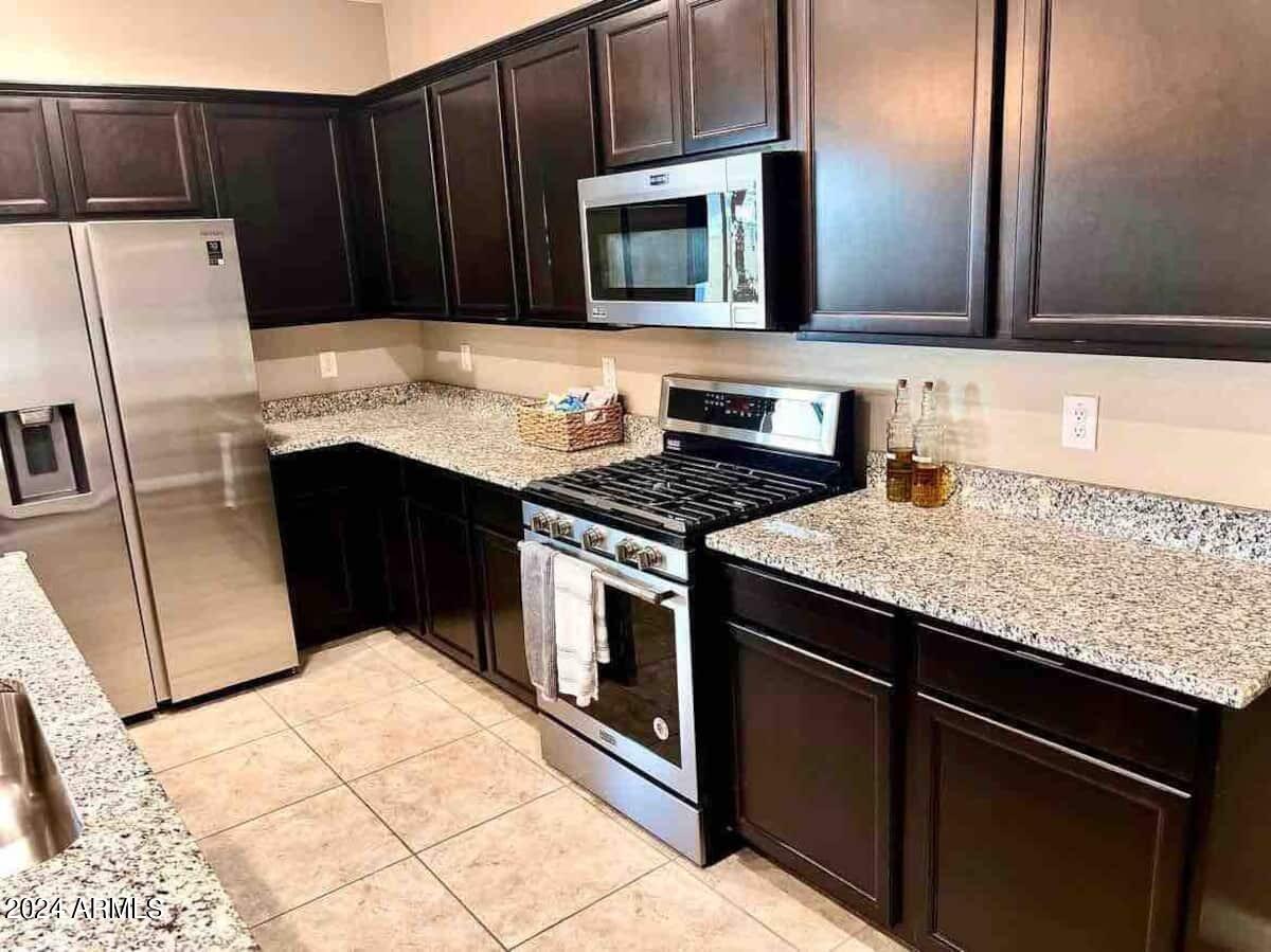 18735 North Ravello Road Maricopa, AZ 85138 - Photo 47 of 50 a kitchen with granite countertop wooden cabinets and stainless steel appliances