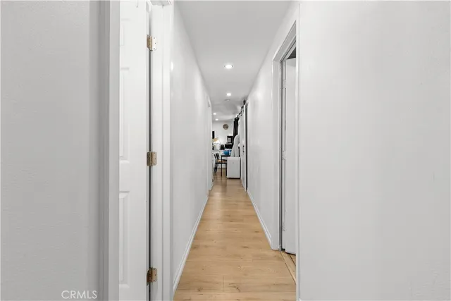 a view of a hallway with wooden floor and a bathroom