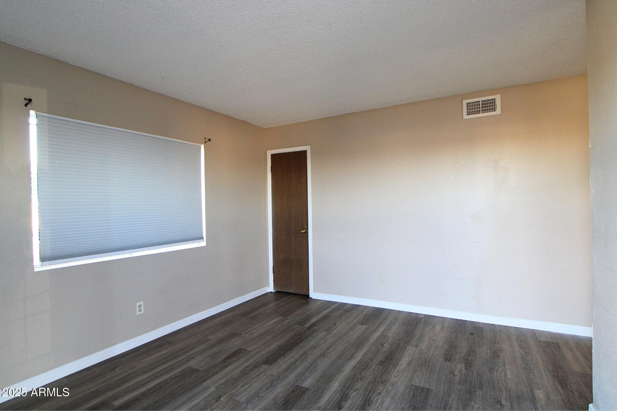 6446 East Alder Avenue, Unit 102 Mesa, AZ 85206 - Photo 2 of 9 a view of an empty room with wooden floor and a window
