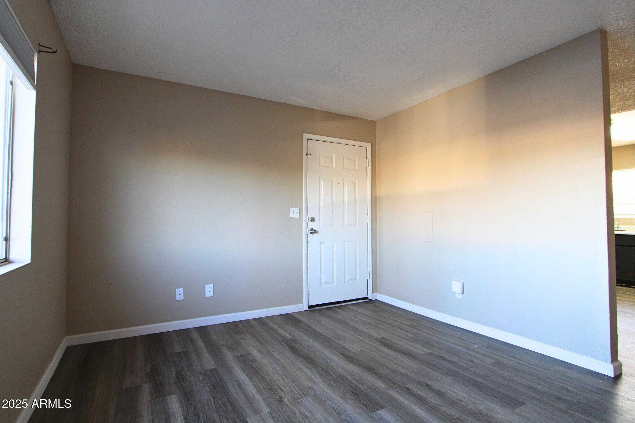 6446 East Alder Avenue, Unit 102 Mesa, AZ 85206 - Photo 3 of 9 an empty room with wooden floor and windows