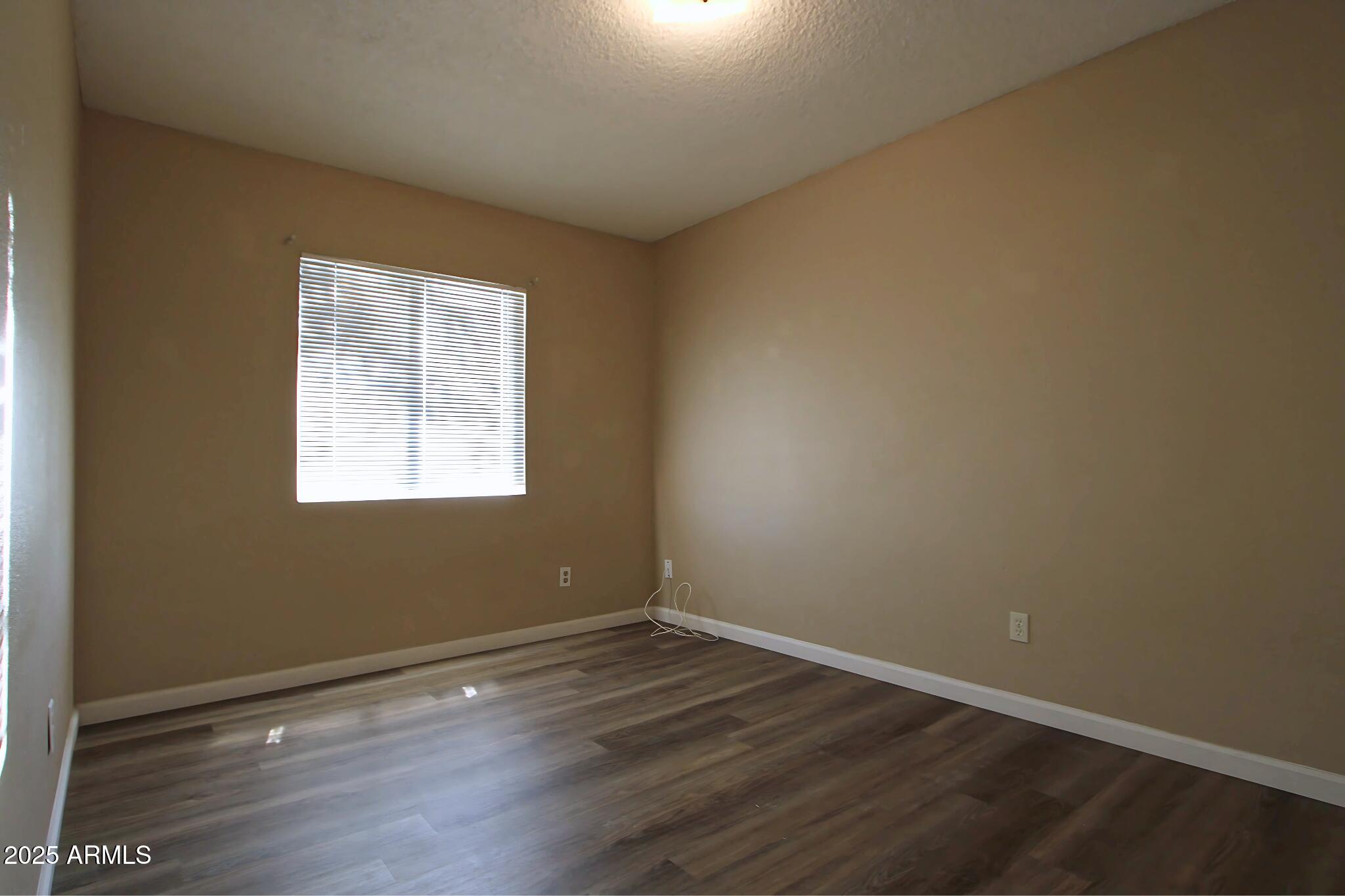 6446 East Alder Avenue, Unit 102 Mesa, AZ 85206 - Photo 4 of 9 an empty room with wooden floor and windows