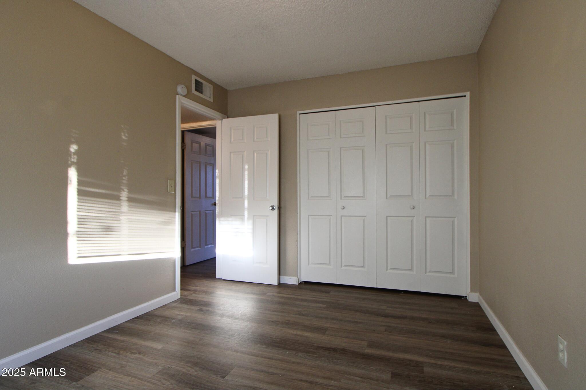 6446 East Alder Avenue, Unit 102 Mesa, AZ 85206 - Photo 5 of 9 an empty room with wooden floor and windows