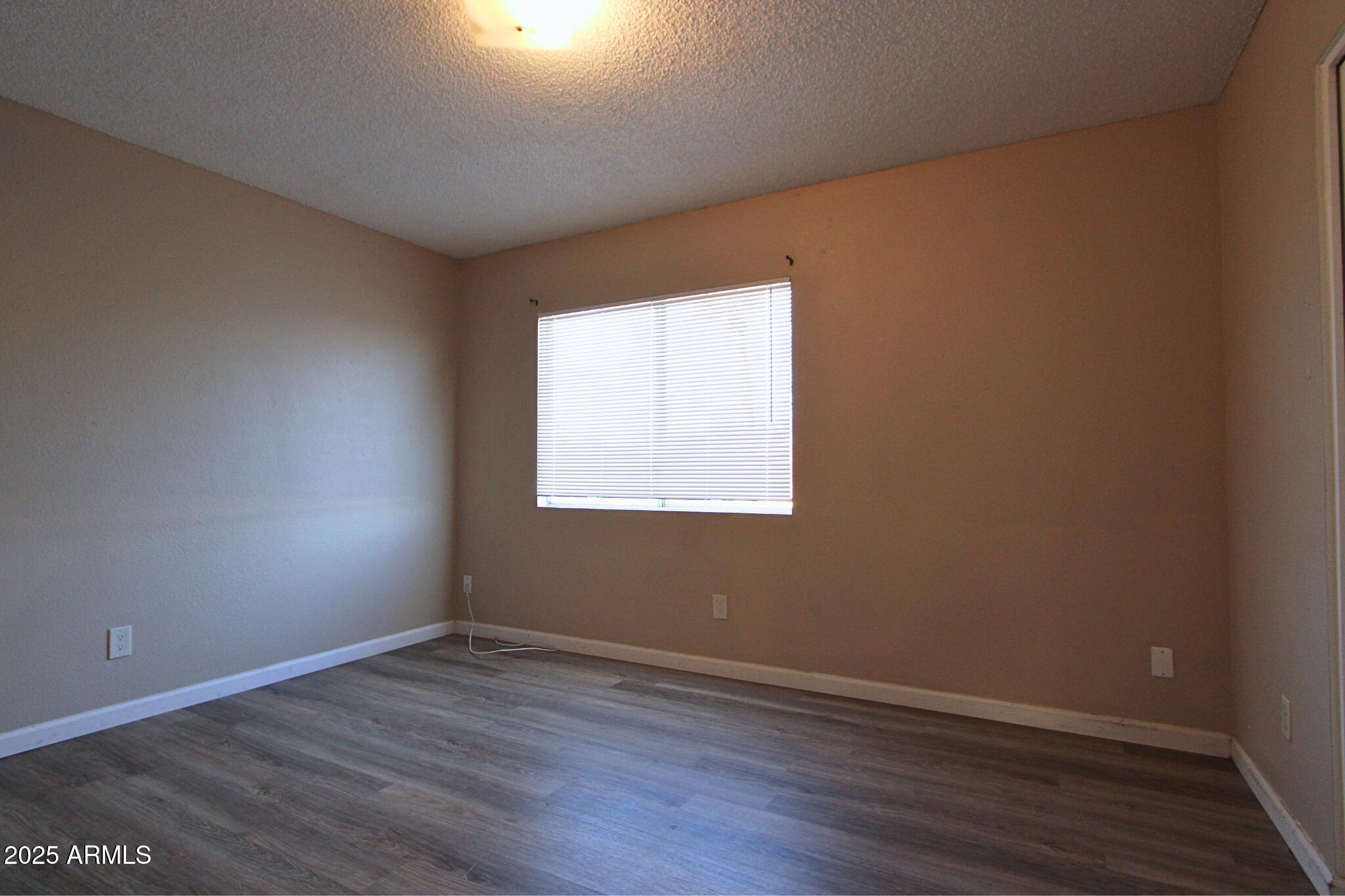 6446 East Alder Avenue, Unit 102 Mesa, AZ 85206 - Photo 7 of 9 an empty room with wooden floor and windows