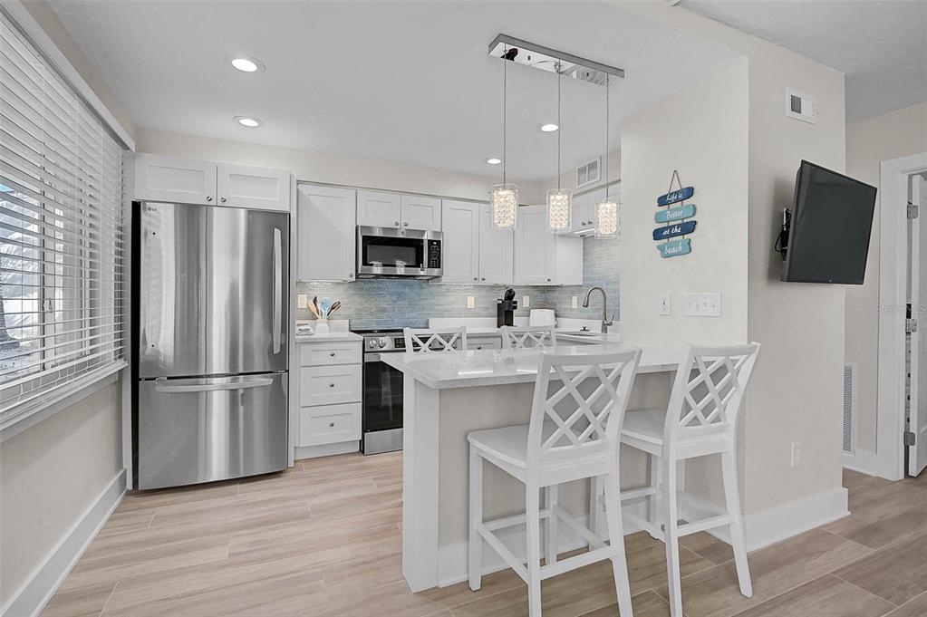 5950 Midnight Pass Road, Unit 101 Sarasota, FL 34242 - Photo 5 of 17 a kitchen with stainless steel appliances kitchen island granite countertop a refrigerator and a stove top oven