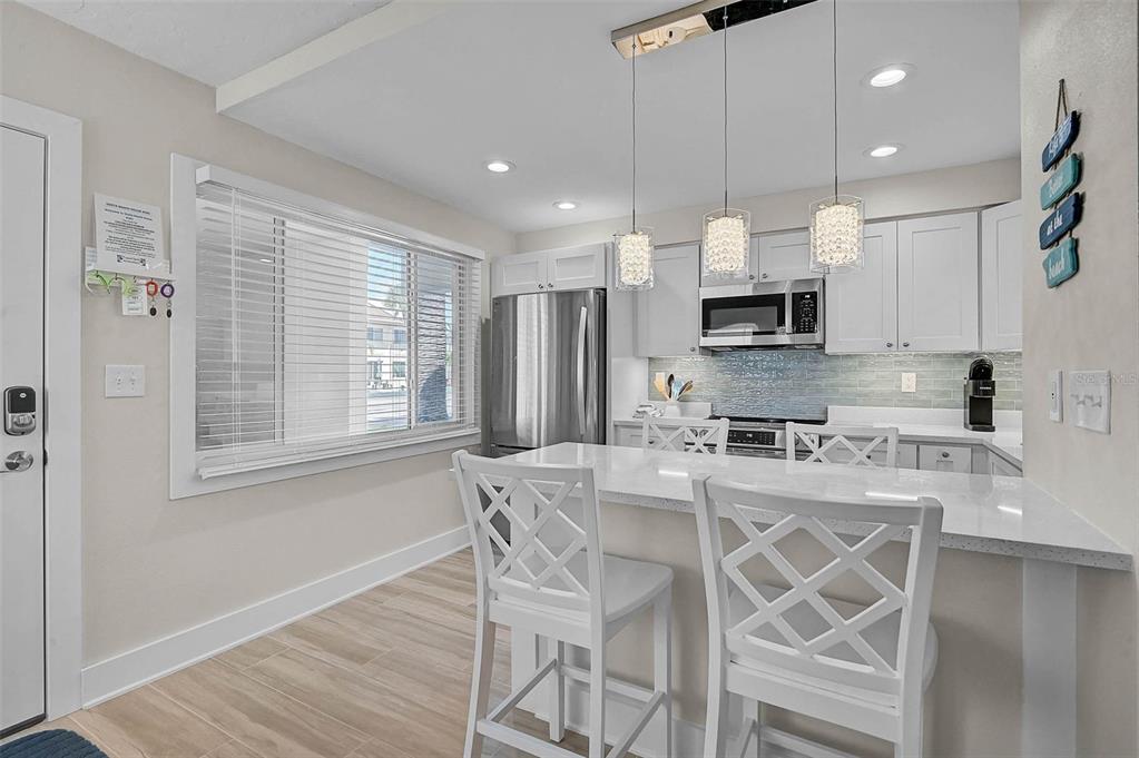 5950 Midnight Pass Road, Unit 101 Sarasota, FL 34242 - Photo 6 of 17 a kitchen with kitchen island granite countertop wooden floors and white cabinets