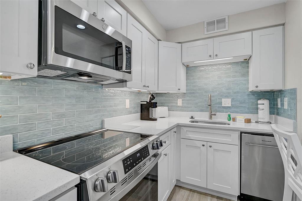 5950 Midnight Pass Road, Unit 101 Sarasota, FL 34242 - Photo 8 of 17 a kitchen with stainless steel appliances granite countertop a sink stove and cabinets