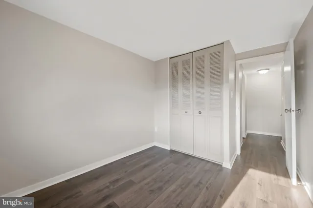 a view of an empty room with wooden floor and a bathroom