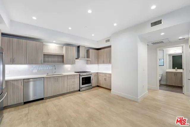 a large white kitchen with a sink a stove and cabinets