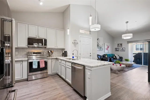 a kitchen with stainless steel appliances a stove top oven a sink dishwasher and a refrigerator with wooden floor