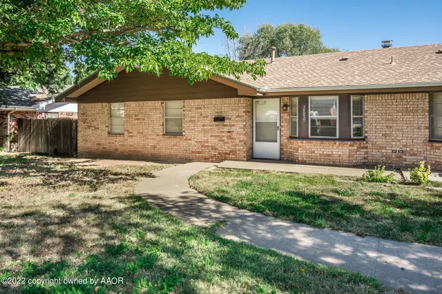 a front view of a house with a yard and potted plants
