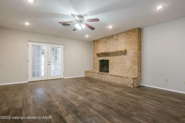 a view of an empty room with window and wooden floor