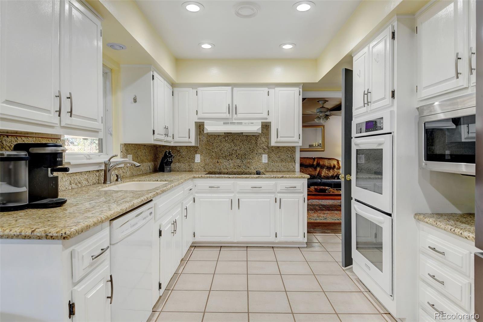 3515 Otis Street Wheat Ridge, CO 80033 - Photo 11 of 37 a kitchen with granite countertop a sink stainless steel appliances and white cabinets