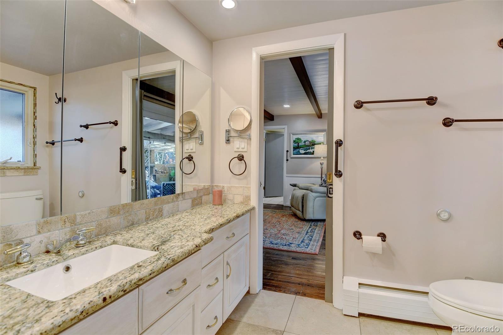 3515 Otis Street Wheat Ridge, CO 80033 - Photo 18 of 37 a bathroom with a granite countertop sink mirror vanity and toilet