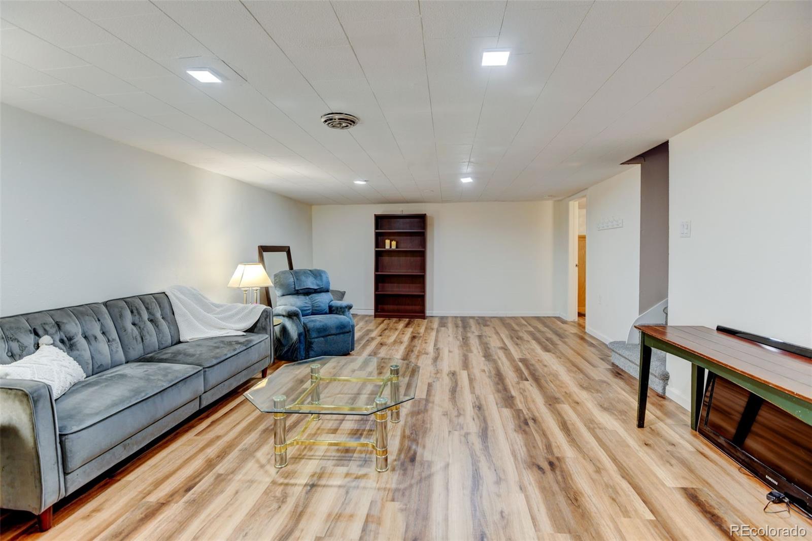 3515 Otis Street Wheat Ridge, CO 80033 - Photo 21 of 37 a spacious bedroom with a bed a couch and a dresser with wooden floor