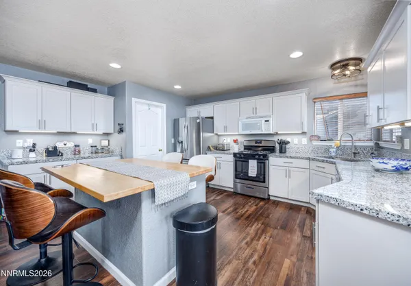 a kitchen with granite countertop stainless steel appliances a stove sink and cabinets