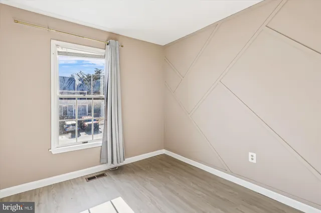 a view of an empty room with window and wooden floor