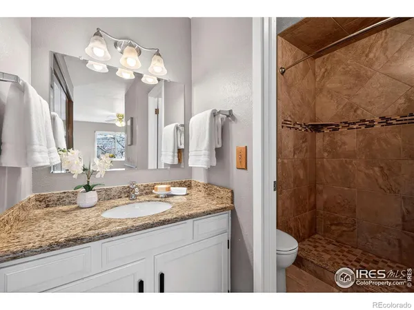 a bathroom with a granite countertop sink a mirror and shower