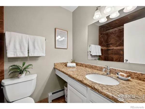 a bathroom with a granite countertop sink a toilet and mirror