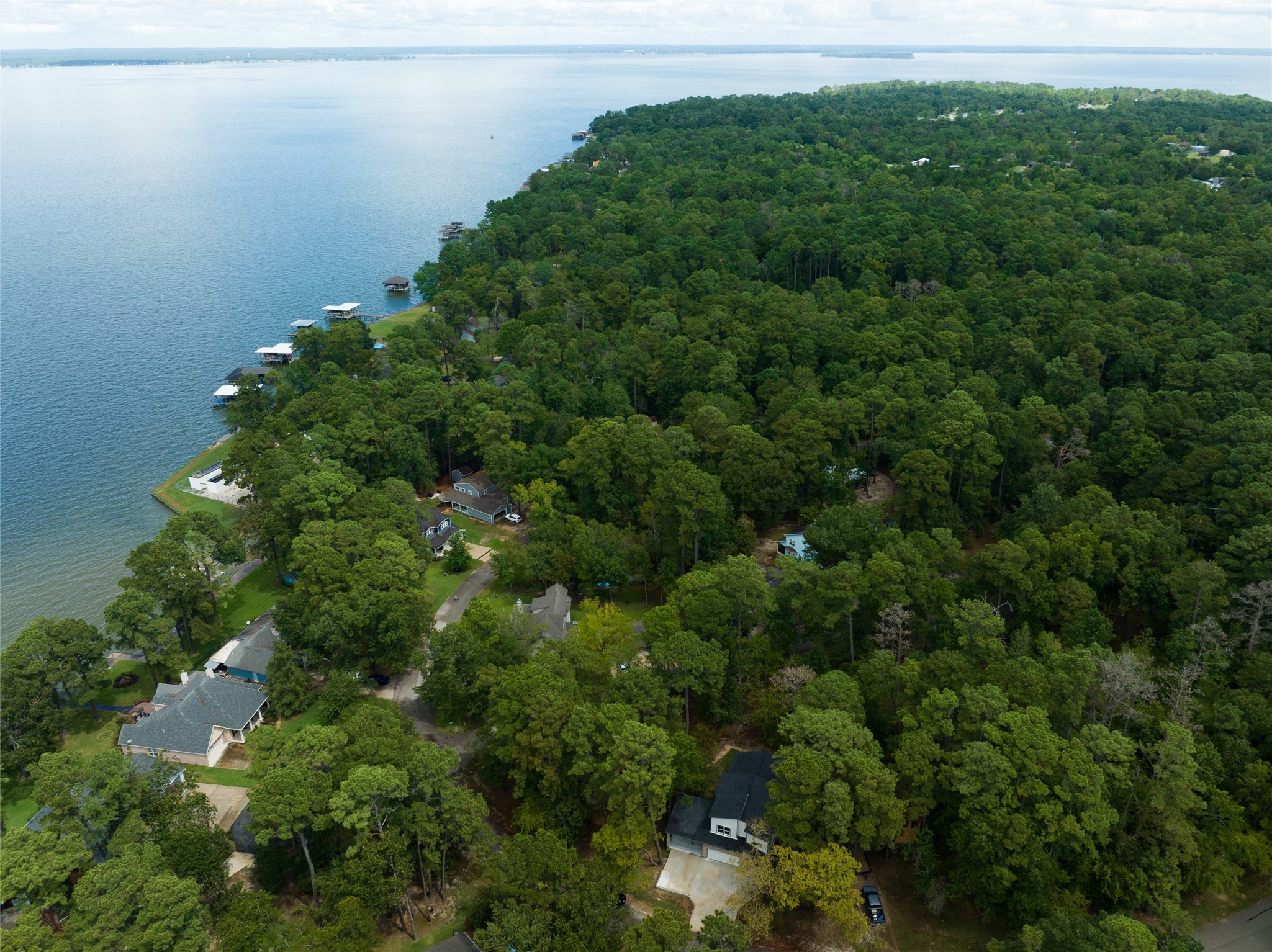 220 North Fairway Loop Coldspring, TX 77331 - Photo 18 of 23 This is an aerial view showcasing a serene lakeside community nestled in a lush forested area, featuring waterfront properties with private docks, offering a tranquil and private living environment with direct access to the water.