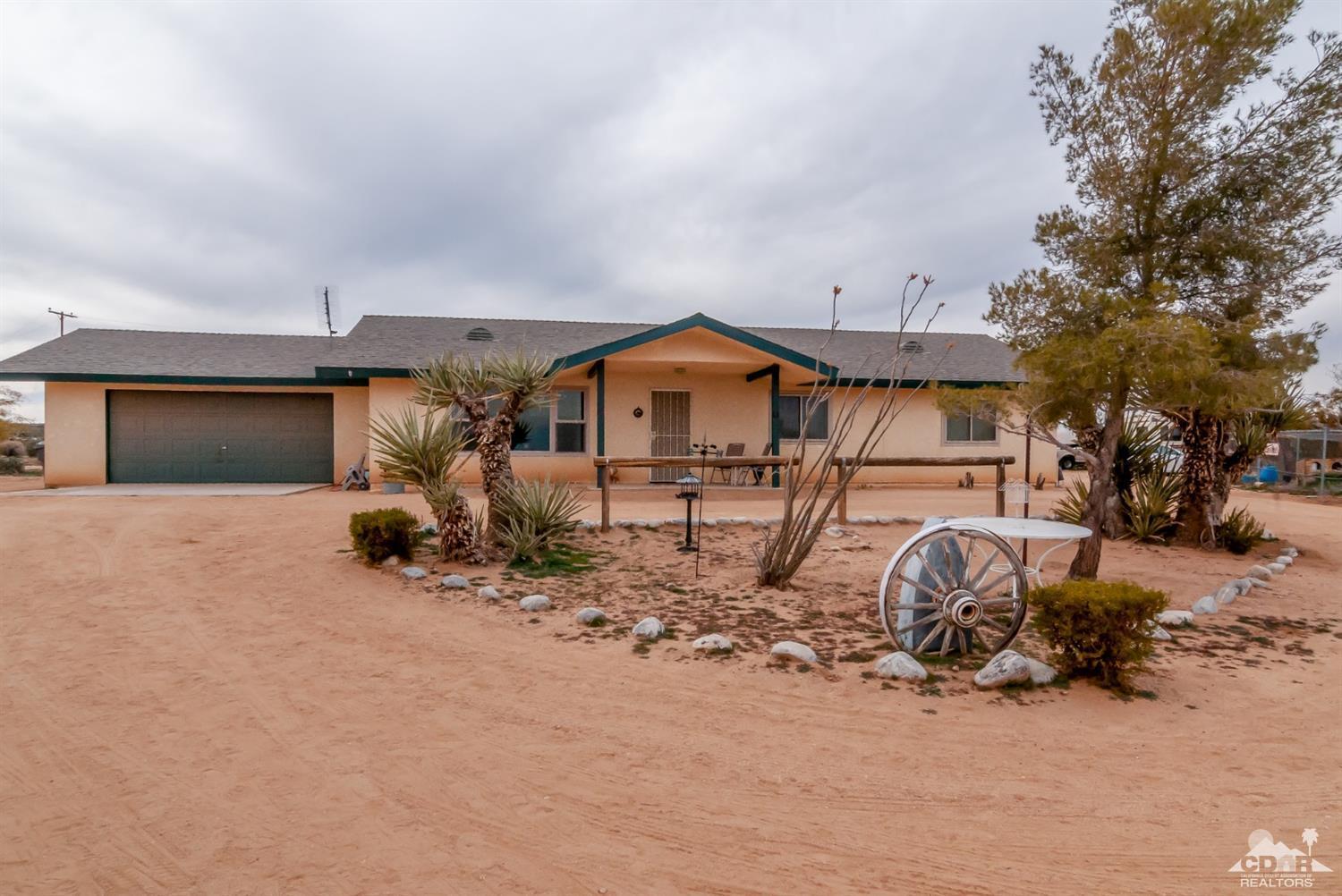 3290 Julcrest Road Yucca Valley, CA 92284 - Photo 1 of 20 a front view of a house with a dirt yard and a large tree