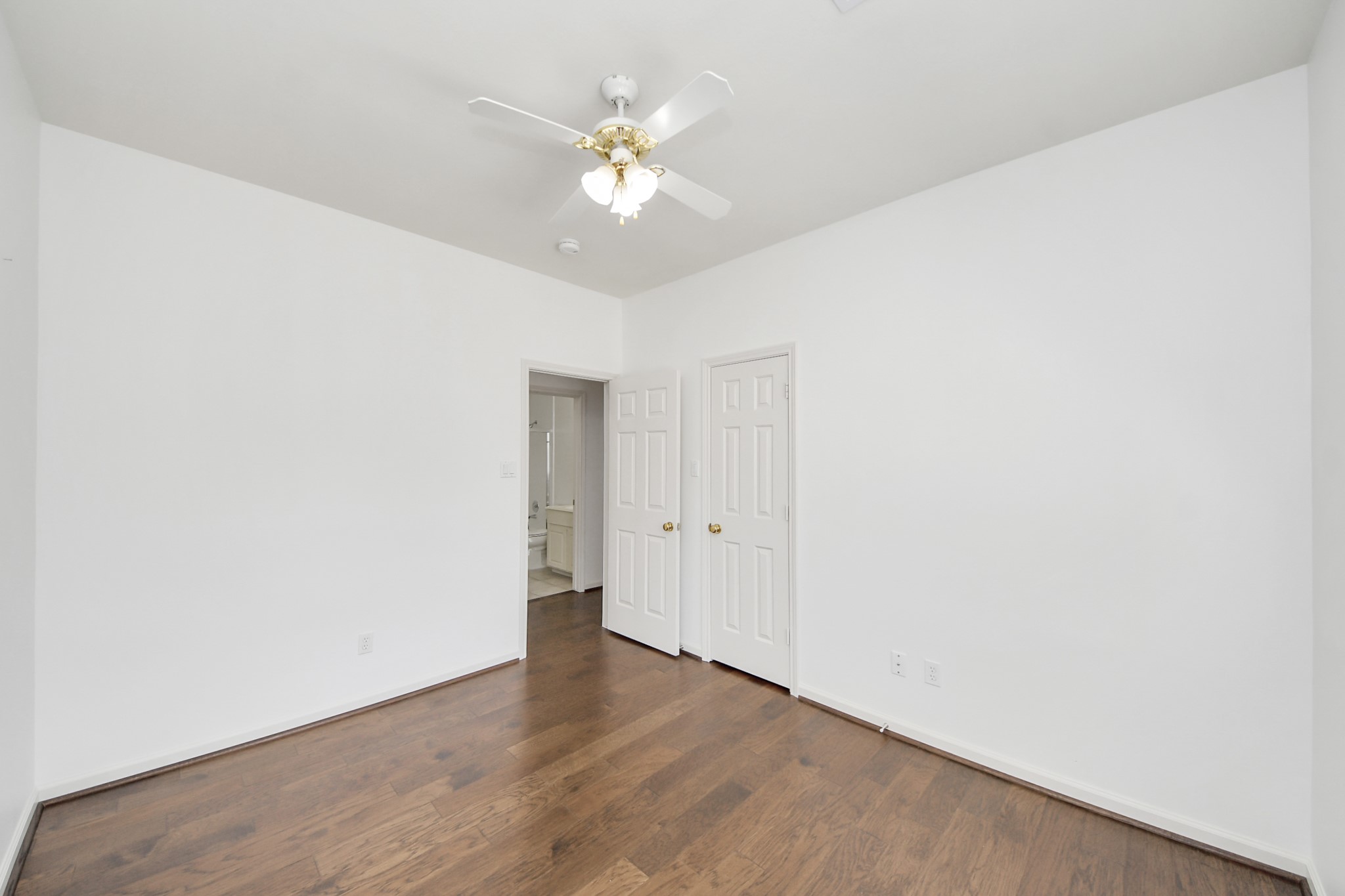 5815 Pheasant Ridge Lane Houston, TX 77041 - Photo 38 of 46 Bright room with elegant hardwood floors, a classic ceiling fan, and a seamless flow into an adjoining bathroom through double doors.