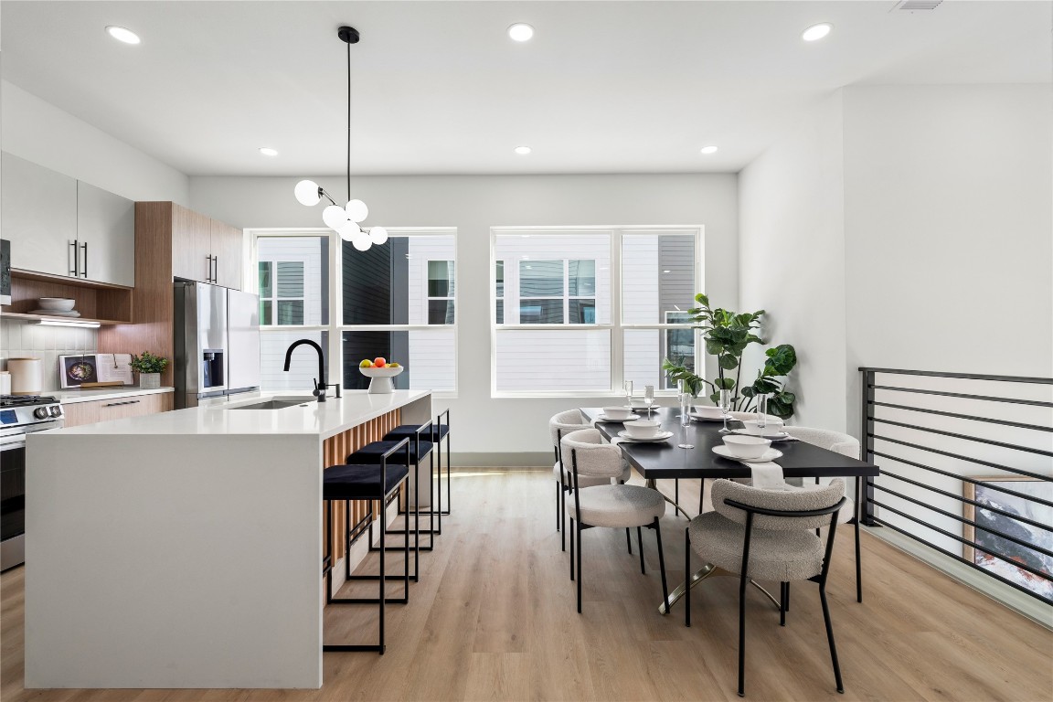 Sleek and functional, this kitchen-dining space is a showcase of elevated design—featuring custom cabinetry, designer lighting, a statement quartz waterfall island, and an open sightline to the living area below.