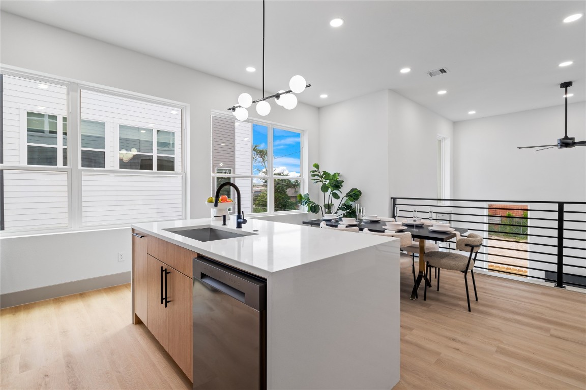 2950 Pitzlin Street Houston, TX 77023 - Photo 16 of 37 Framed by walls of windows and modern horizontal railings, this elevated kitchen and dining space invites natural light to pour in—highlighting the crisp quartz countertops, sleek matte black fixtures, and seamless indoor-outdoor flow. It's a setting designed for connection, conversation, and everyday luxury.